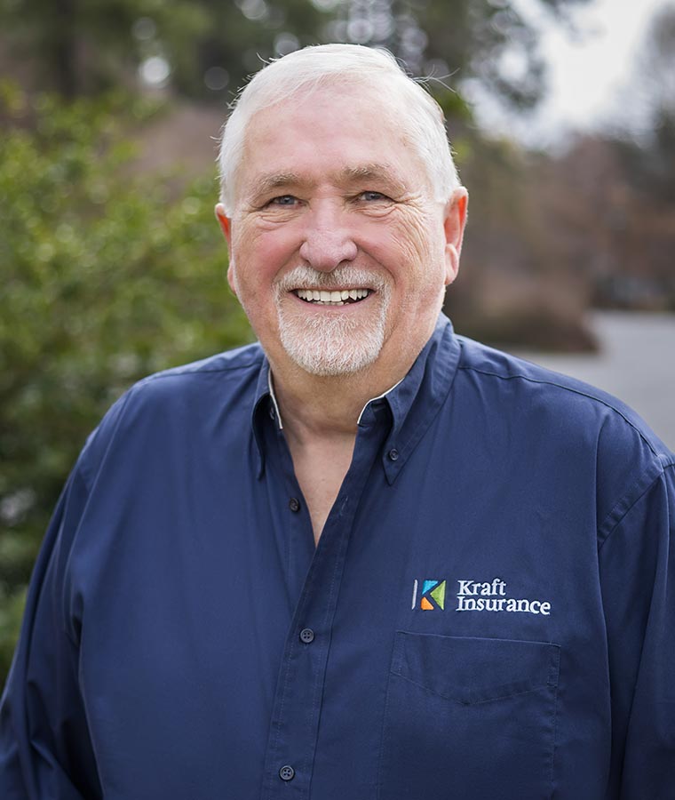 Bill Zimmer in Kraft Insurance shirt smiling outdoors.