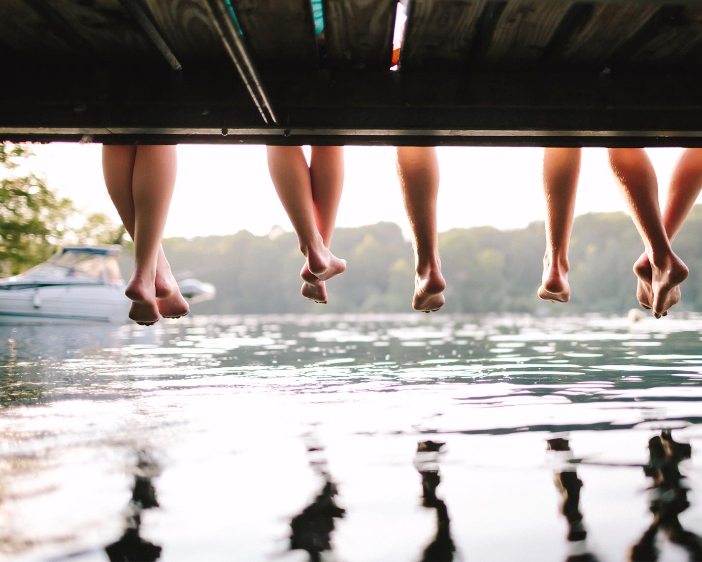 People sitting on a dock with legs dangling above the water.